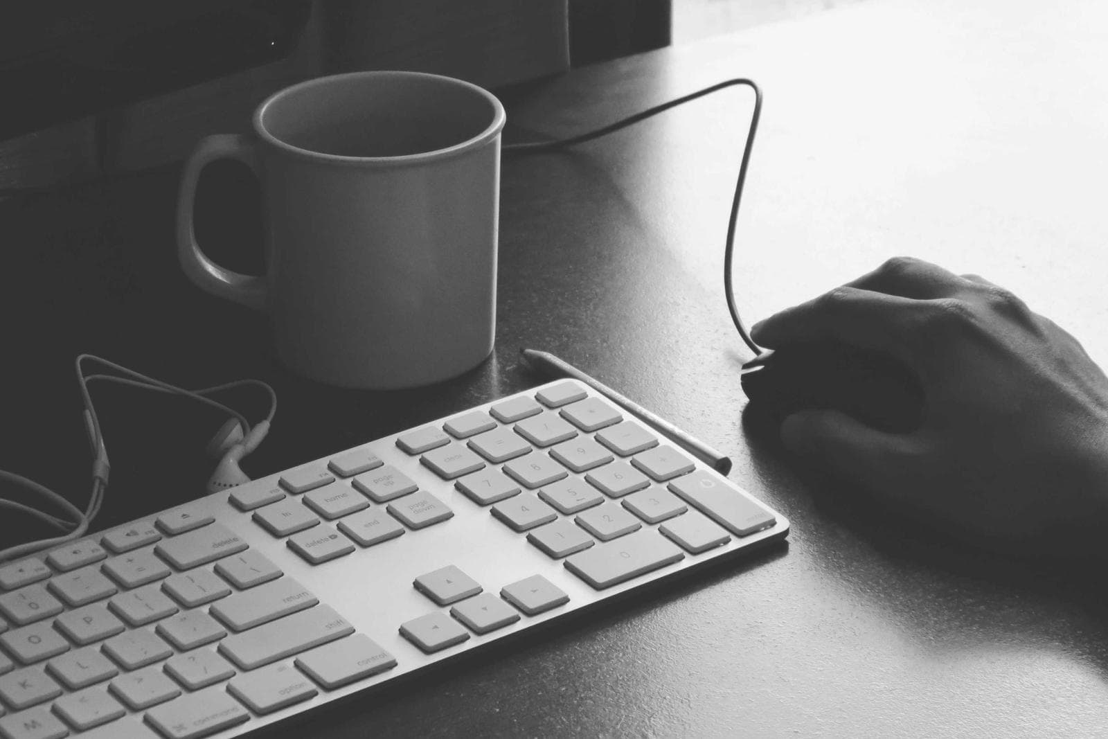 Hands on a keyboard and mouse next to a coffee mug